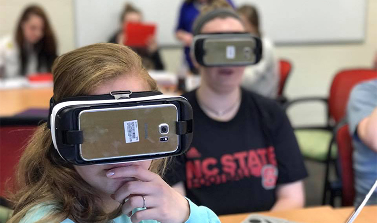 Students in a classroom wearing virtual reality headsets.